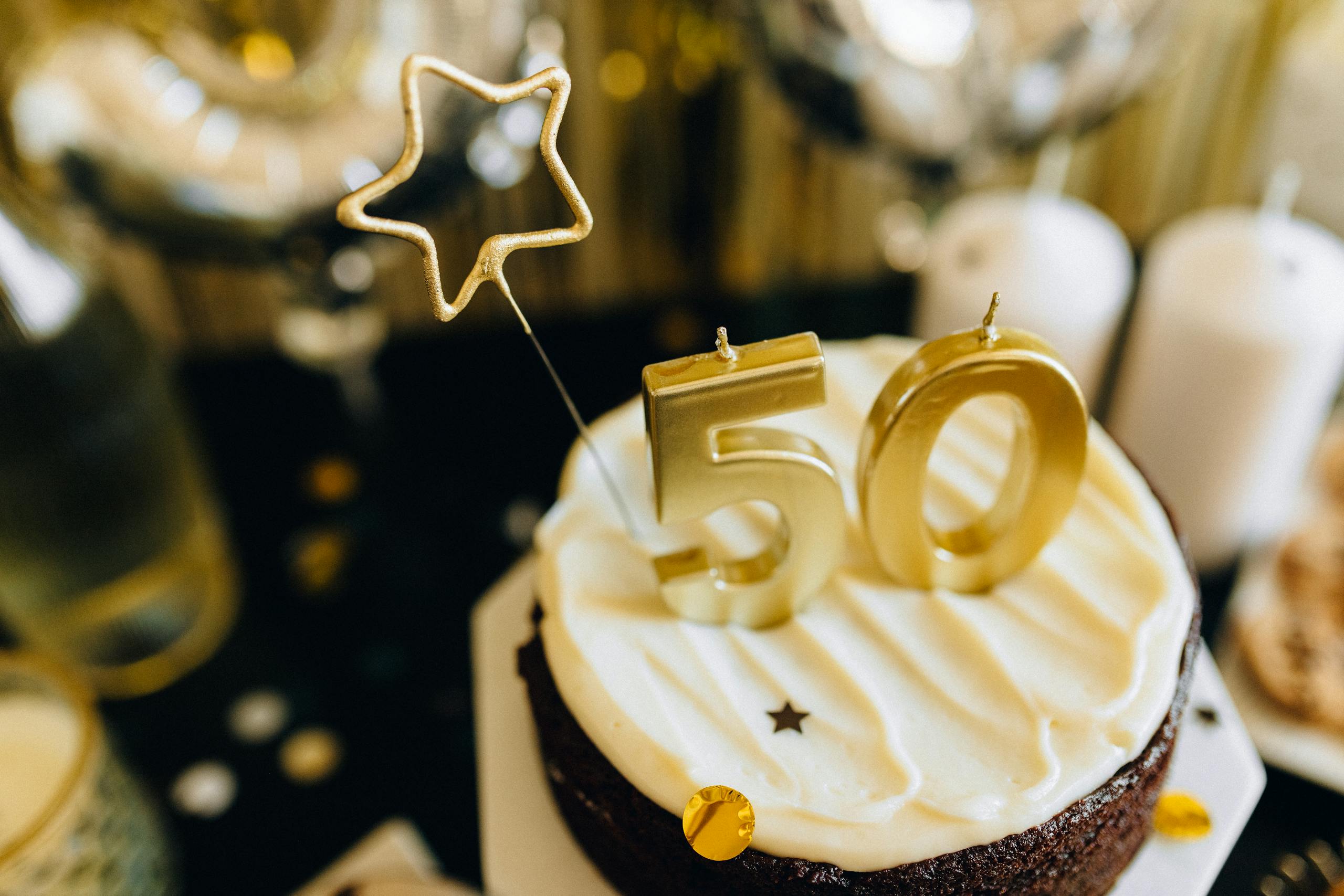 Elegant cake with golden 50th birthday topper and star decorations.